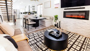 Una sala de estar moderna con chimenea, un comedor y una cocina al fondo.