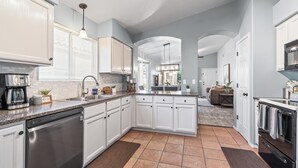 A modern kitchen with white cabinets, a dishwasher, and a central island. - Serene Vacation Home - Trails, Golf & Dining! (Marana)