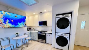 Una cocina compacta con gabinetes blancos, un microondas integrado, una estufa y una lavadora y secadora de doble puerta.