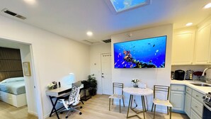 Una cocina moderna con comedor, un televisor mostrando una escena submarina y una pequeña mesa con sillas.