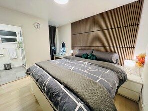 Un dormitorio moderno con cama, mesita de noche, espejo y una pared con listones de madera verticales.