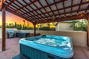 A hot tub under a pergola with a sunset view, outdoor kitchen, and cactus plants. - La Puerta Azul - Stunning Desert Retreat Pool Spa (Tucson)