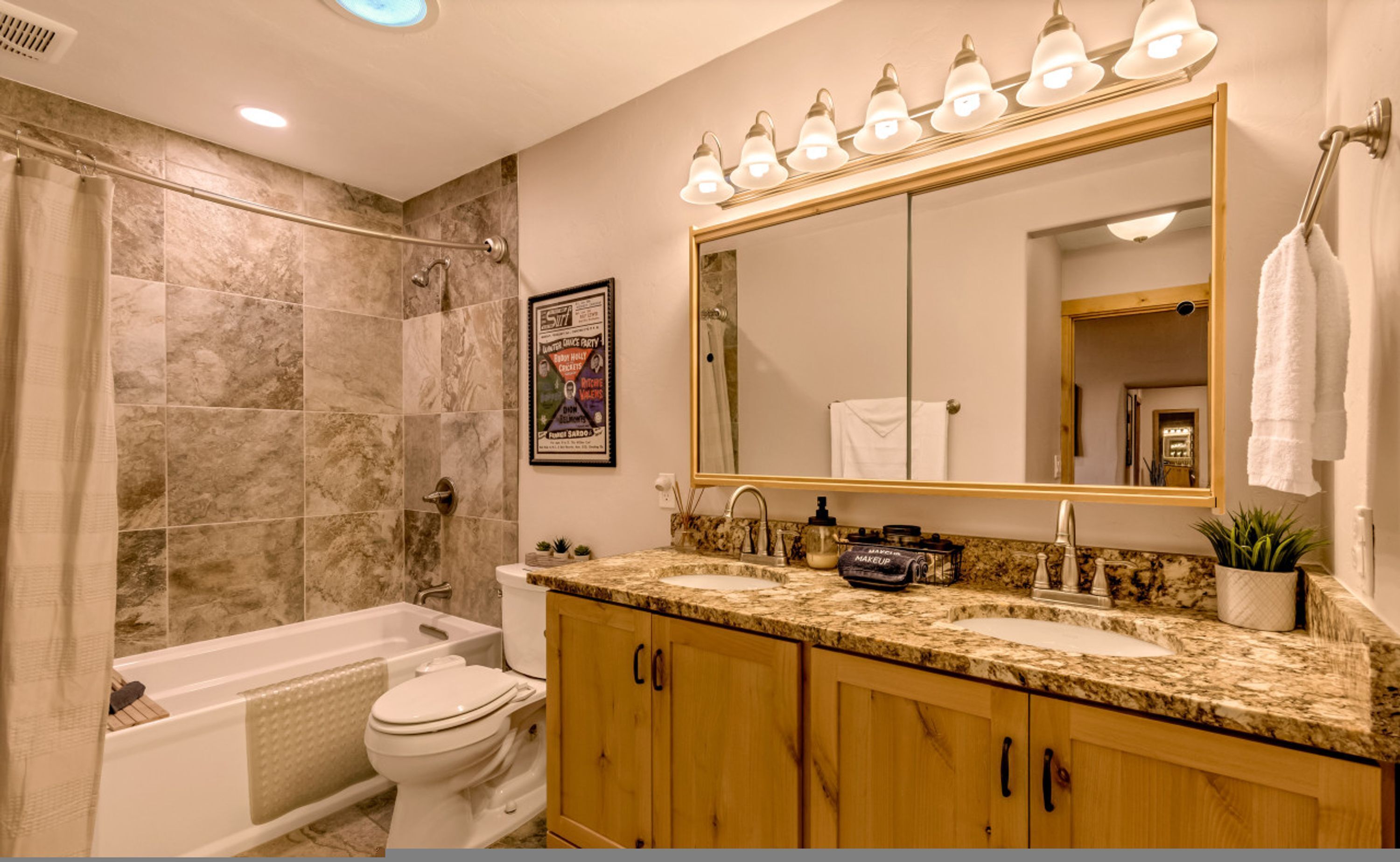A bathroom with a bathtub, toilet, and sink. There is a large mirror above the sink and a shower area with a glass door.
