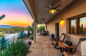 A covered patio with stone flooring, outdoor furniture, and potted plants. - La Puerta Azul - Stunning Desert Retreat Pool Spa (Tucson)