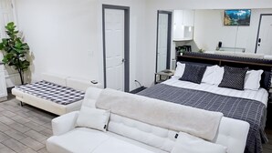 A hotel room with a bed, a sofa, a small table, a mirror, and a plant.