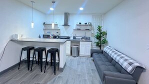 A compact kitchen with a central island, bar stools, a sink, and a stove.