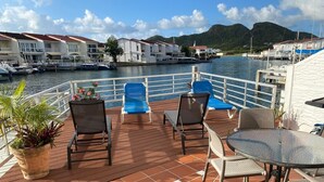 Una terrazza con sedie e tavolo che si affaccia su una marina con barche e case.