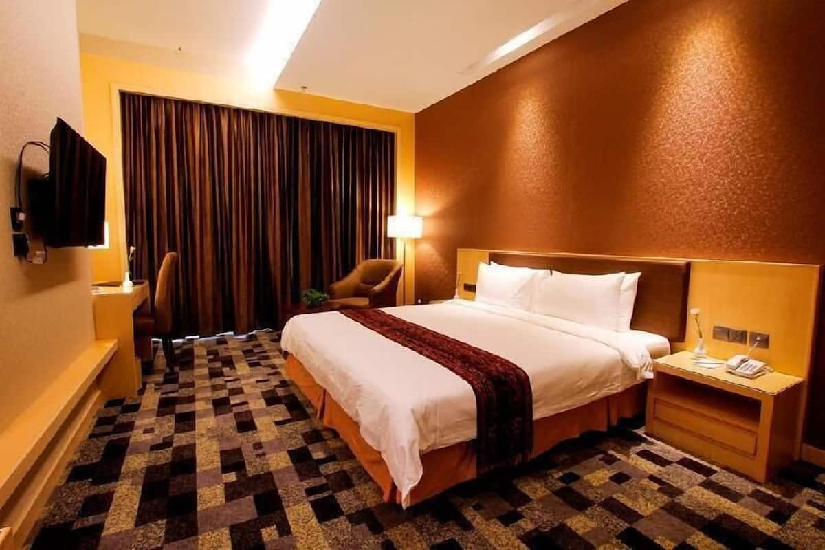 Una habitación de hotel con una cama, una silla, un escritorio, una lámpara y un televisor.