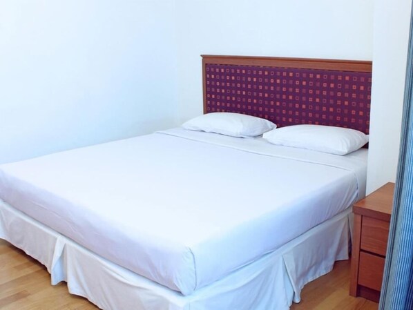 A single bed with white bedding, a wooden headboard with a patterned design, and a wooden nightstand to the right. - Imperial Hotel Miri (Miri)