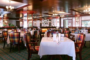 Un restaurante con varias mesas y sillas, algunas con tapicería escocesa.