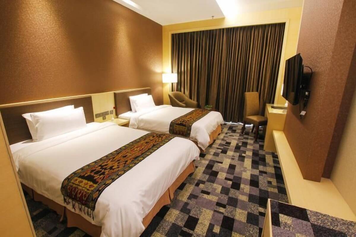 Una habitación de hotel con dos camas, televisión, escritorio y una silla.