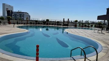 A swimming pool with a tiled deck, a safety cone, and a metal handrail.