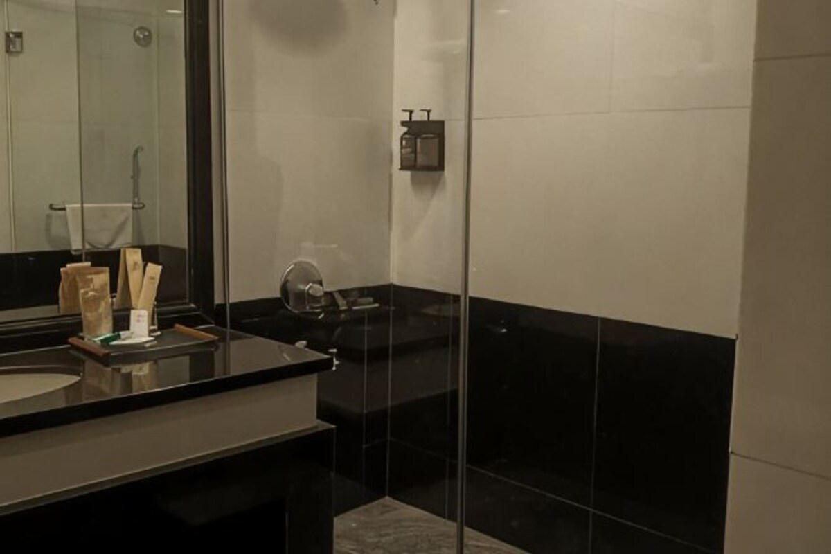 A modern bathroom with a glass shower enclosure, a black countertop, and a mirror.