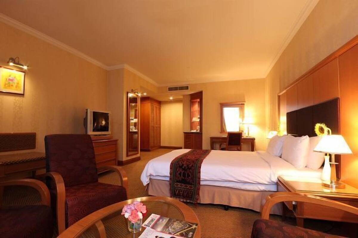 Una habitación de hotel con una cama, un escritorio, una silla, un televisor y una lámpara.