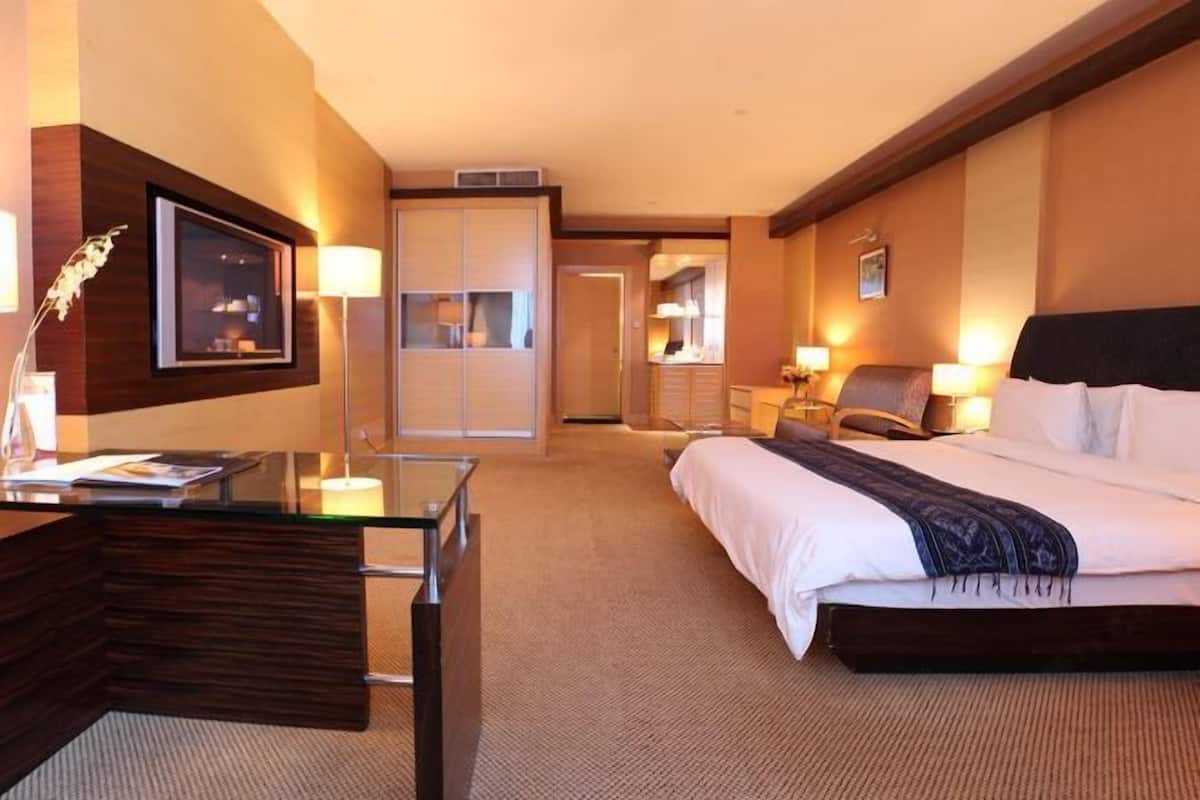Una habitación de hotel con cama, escritorio, silla y puerta que da a un baño.