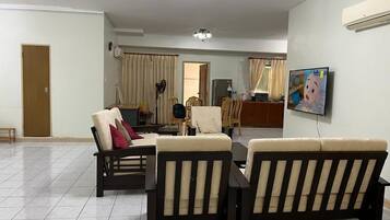 Una sala de estar con un sofá, una televisión y un comedor con sillas y una mesa.