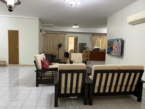 A living room with a sofa set, a television, and a dining area with chairs and a table. - Imperial Hotel Miri (Miri)