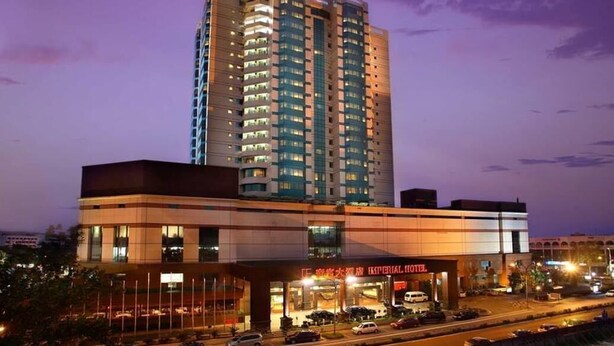 Un hotel de varios pisos con fachada moderna, estacionamiento y vistas despejadas del entorno.
