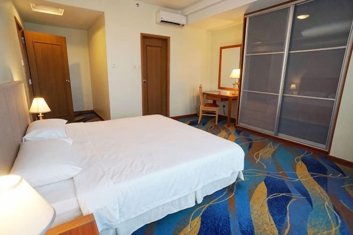 A hotel room with a bed, a desk, a chair, and a large window.