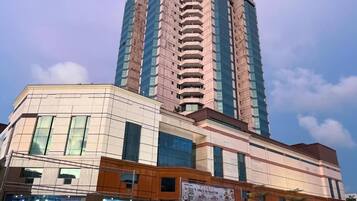 A multi-story building with a modern architectural design, featuring a prominent central tower and a ground-level commercial area with visible signage.