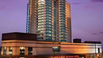 A multi-story hotel building with a modern design, featuring a prominent entrance and a parking area in front.