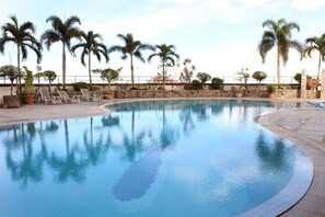 A swimming pool with a curved edge, surrounded by palm trees and lounge chairs. - Imperial Hotel Miri (Miri)