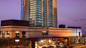 Un hotel moderno de gran altura con varios pisos, un restaurante en la planta baja y un área de estacionamiento.