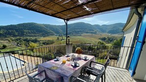 A balcony with a table set for two, overlooking a scenic valley.