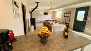 A dining area with a table set for four, a black stove, and a fruit bowl on the counter.
