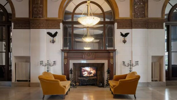 A spacious lobby with a fireplace, two armchairs, and a chandelier. - Luxe Suite one bedroom condo with ocean view balcony and free secure parking (Long Beach)