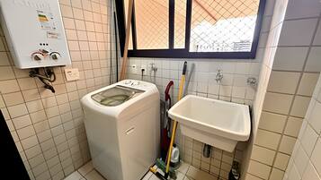 A compact kitchen with a washing machine, a sink, and a window.