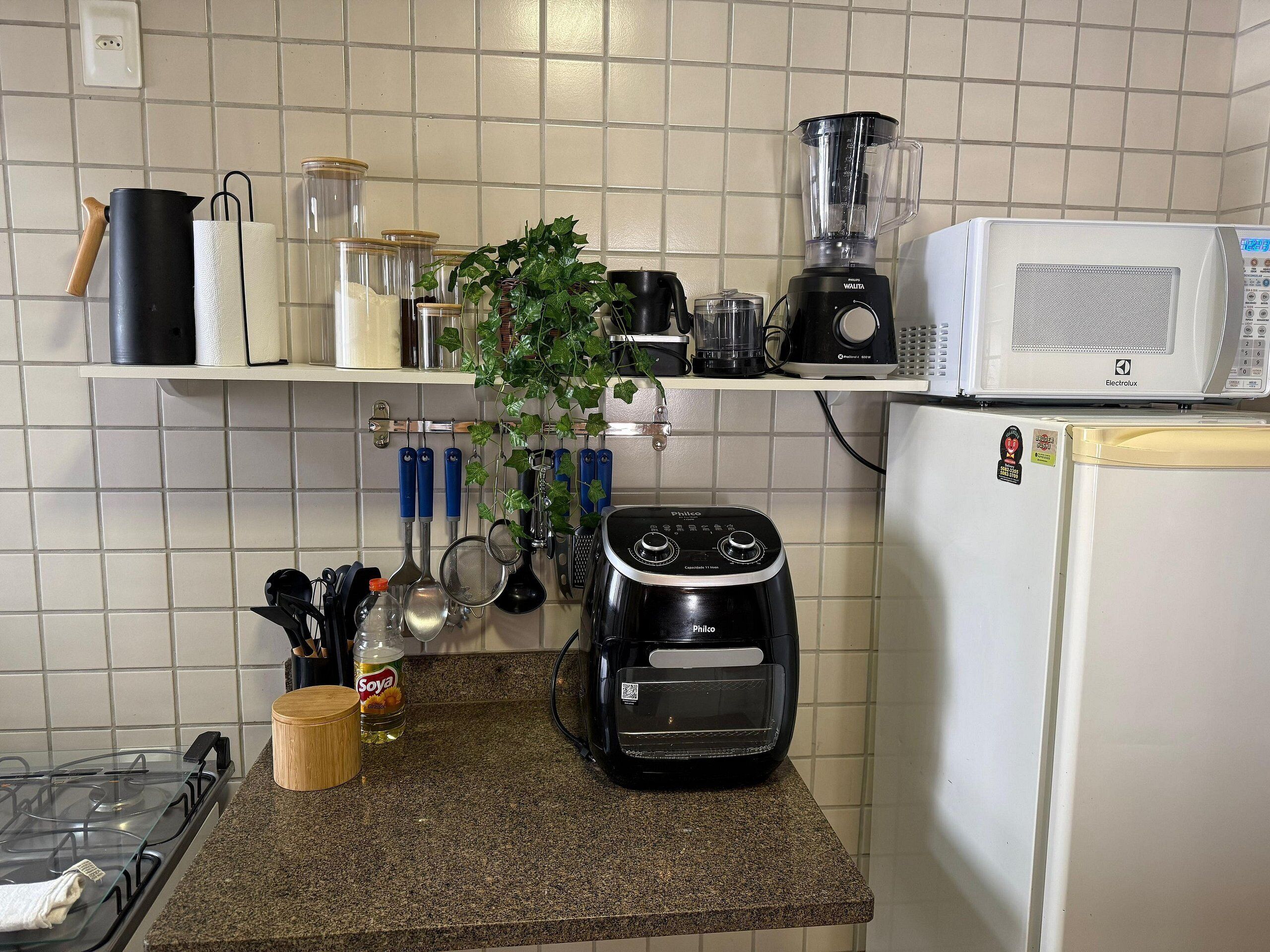 Una cocina con estufa a gas, licuadora, microondas y diferentes utensilios de cocina.