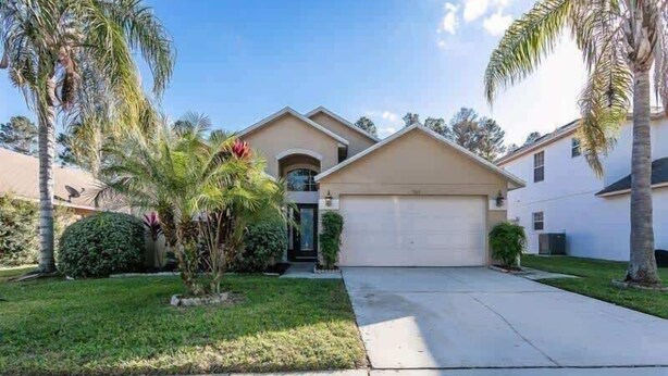 A residential house with a garage, a front lawn, and palm trees. - Beautiful South Facing Pool Home (Kissimmee)