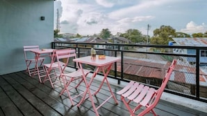 A balcony with pink metal furniture, including chairs and a table, overlooking a residential area with houses and a clear sky. - Ellys Home (Semporna)