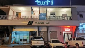 A two-story building with a neon sign reading "ELLY'S HOME" and a sign for "TABUNG HAJI" below. - Ellys Home (Semporna)