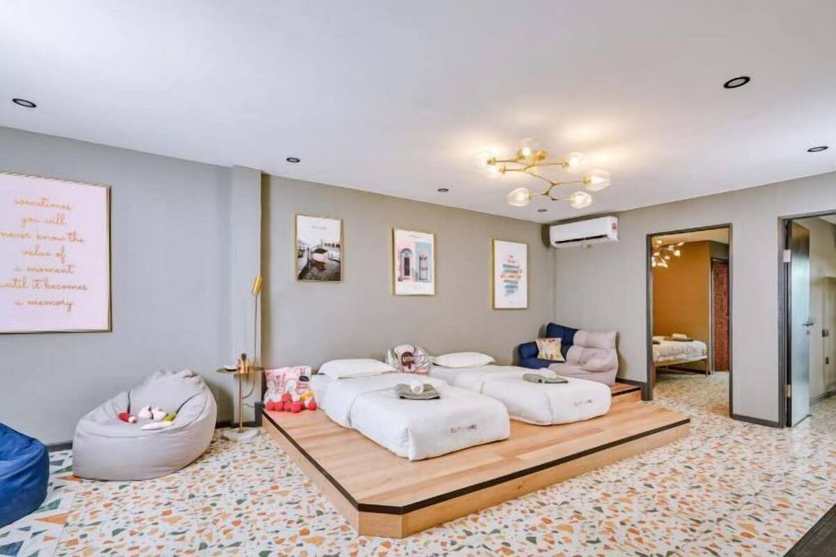 A room with a bed, a bean bag, a small table, and a wall with framed pictures.