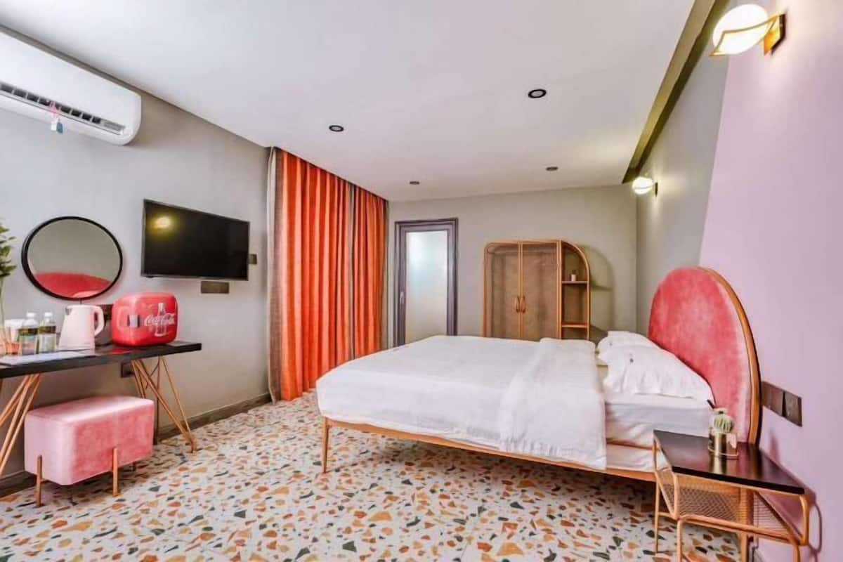 A hotel room with a bed, a desk with a chair, a television, and a wardrobe.