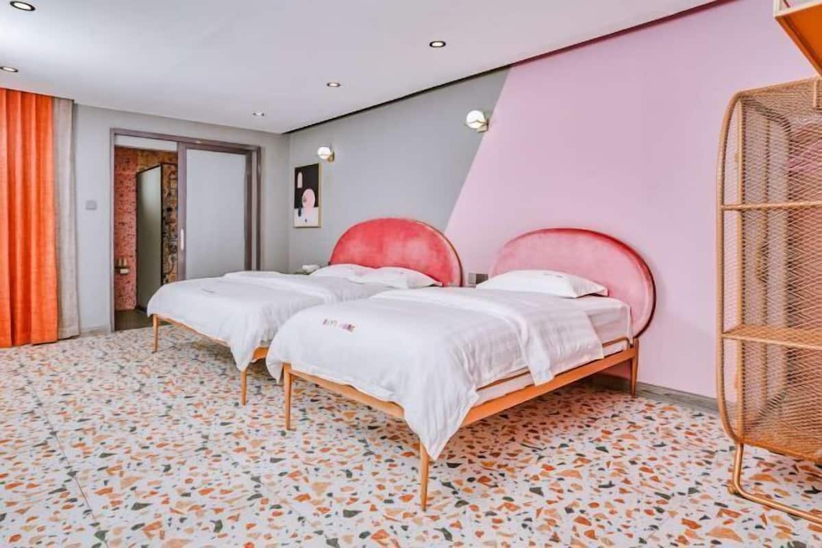 A bedroom with two beds, a mirror, a door, and a wall with a geometric design.