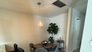 A dining area with a round table, four chairs, a hanging light fixture, a potted plant, and a wine rack. - River Ranch condo with Pool (Lafayette)