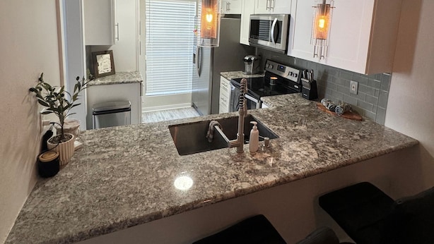 A kitchen with granite countertops, stainless steel appliances, and pendant lighting. - River Ranch condo with Pool (Lafayette)