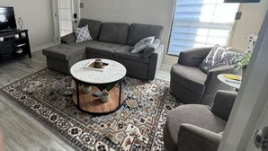 A modern living room with a grey sectional sofa, a round coffee table, and a patterned rug. - River Ranch condo with Pool (Lafayette)