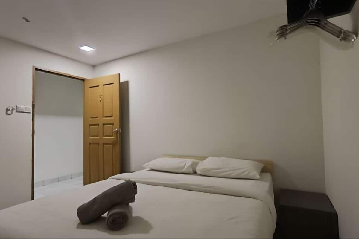 Une chambre à coucher avec un lit, une porte en bois et une table de chevet.
