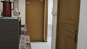 A hallway with a patterned rug, a red kettle on a counter, and a wooden door. - Natol Homestay-MJC Batu Kawa MJC New Township (Kuching)