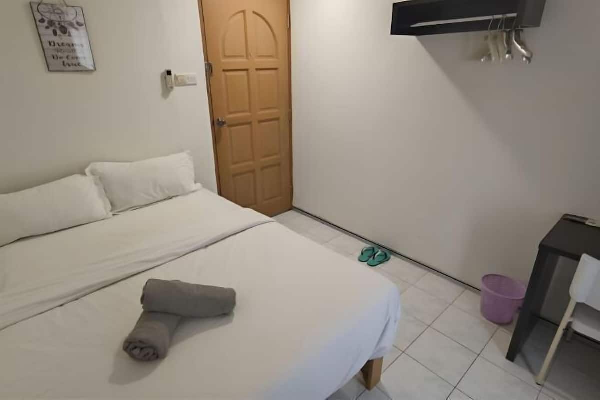 Une chambre avec un lit, un bureau, une porte et un téléviseur fixé au mur.