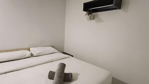 A clean, minimalist hotel room with a neatly made bed, a wall-mounted light switch, and a small shelf with a fork. - Natol Homestay-MJC Batu Kawa MJC New Township (Kuching)