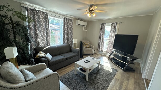 A living room with a sofa, armchair, coffee table, TV, and a ceiling fan. - Beautiful Downtown Core Apt. Located on Main Street, Kentville (Kentville)