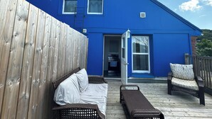 A blue house with a deck, a wooden fence, and outdoor furniture including a sofa and chairs. - Beautiful Downtown Core Apt. Located on Main Street, Kentville (Kentville)