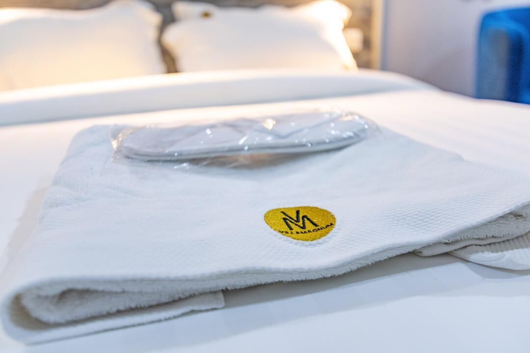 Una toalla blanca doblada con un logotipo sobre una cama.