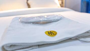 Una toalla blanca doblada con un logotipo sobre una cama.
