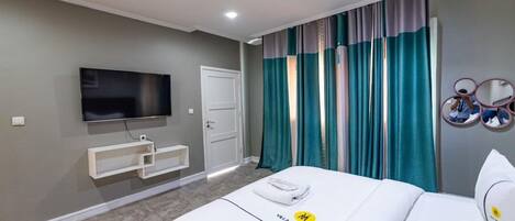 Una camera d'albergo con un letto, una televisione, una porta e delle tende.